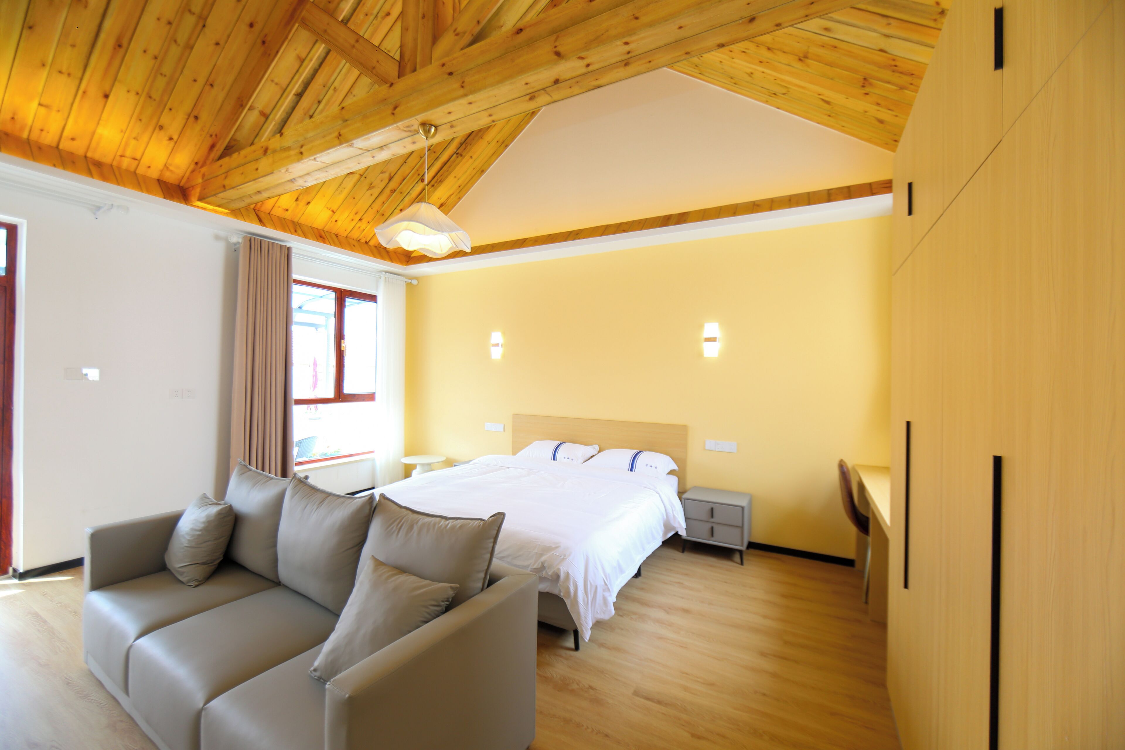 Une chambre moderne avec un plafond en bois, un grand lit, un canapé et une table de chevet.