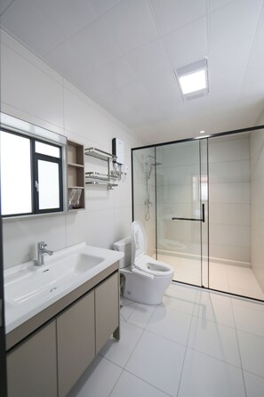 A modern bathroom with a glass shower enclosure, a white sink, and a toilet. - JOYSEA HUT (Yantai)