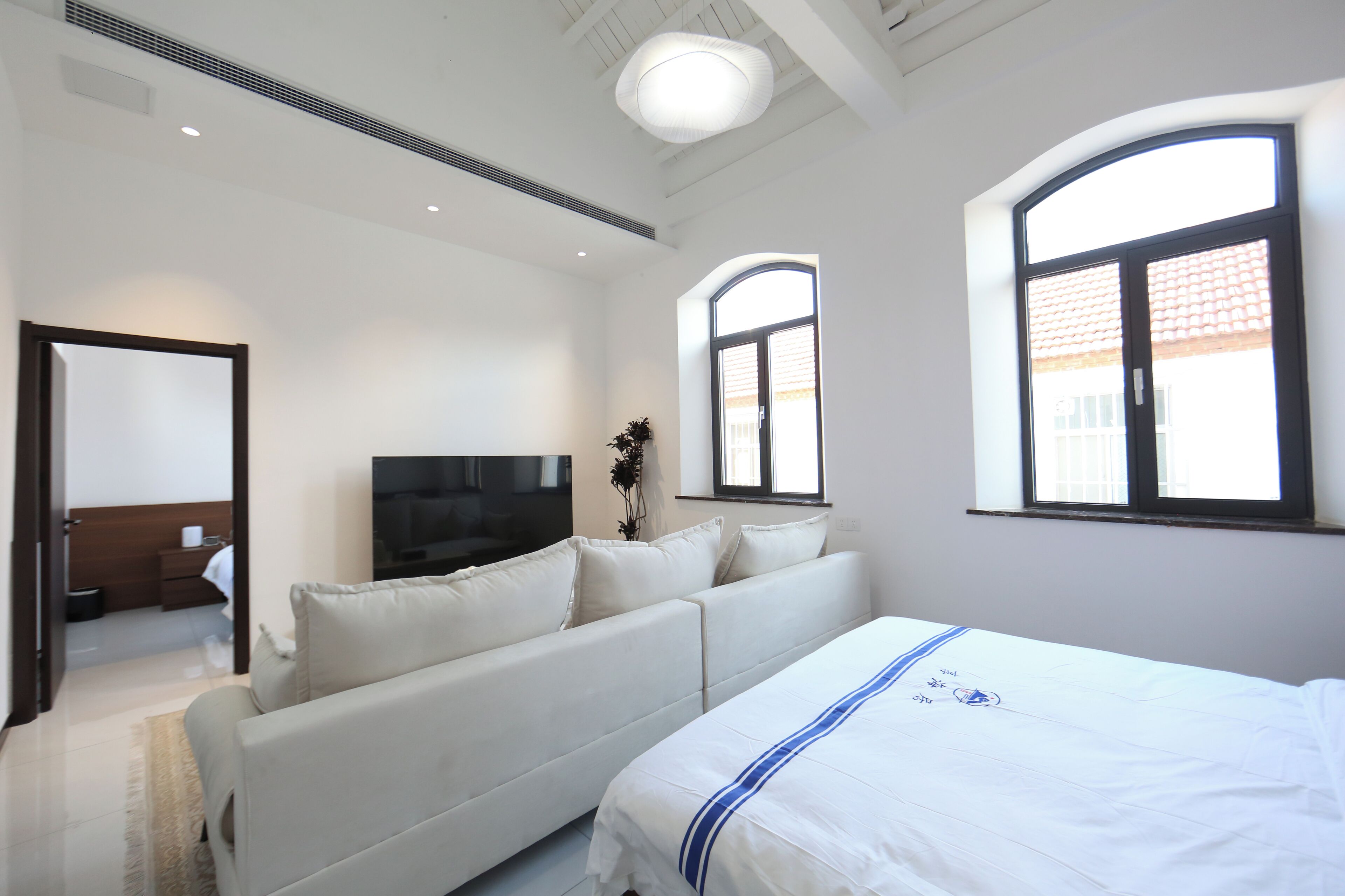 Une chambre d’hôtel moderne dotée d’un grand lit, d’un canapé, d’une télévision à écran plat et de grandes fenêtres.