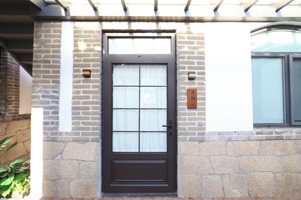 A brown door with a glass panel, set in a stone wall with a small plaque. - JOYSEA HUT (Yantai)