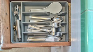 Un tiroir contenant divers ustensiles de cuisine, notamment des cuillères, des fourchettes et une paire de ciseaux.