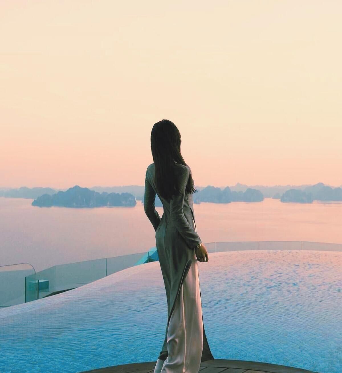 A person standing by a body of water with a view of distant landforms.
