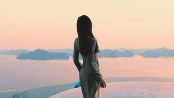A person standing by a body of water with a view of distant landforms.