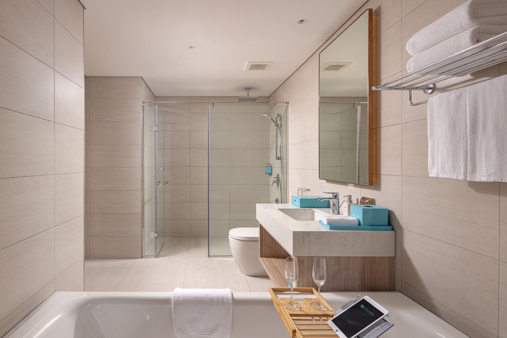 Un baño moderno con cabina de ducha de vidrio, bañera, tocador con espejo e inodoro.