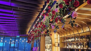 A bar area with a modern design, including a ceiling with wooden slats and hanging floral decorations. - Alacarte Ha Long Bay Managed by Navis Global (Bai Chay)