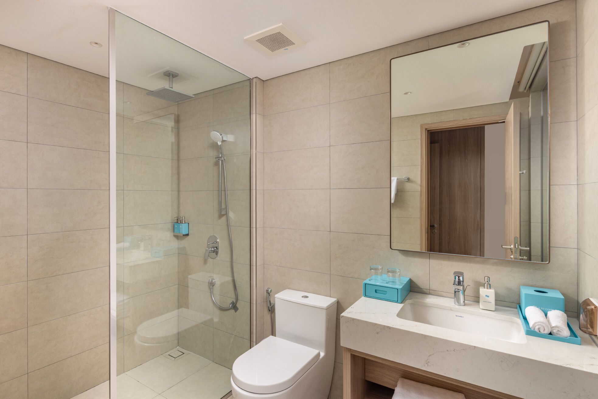 Une salle de bain moderne avec une douche en verre, des toilettes, un lavabo avec un miroir et un meuble-lavabo avec des articles de toilette.