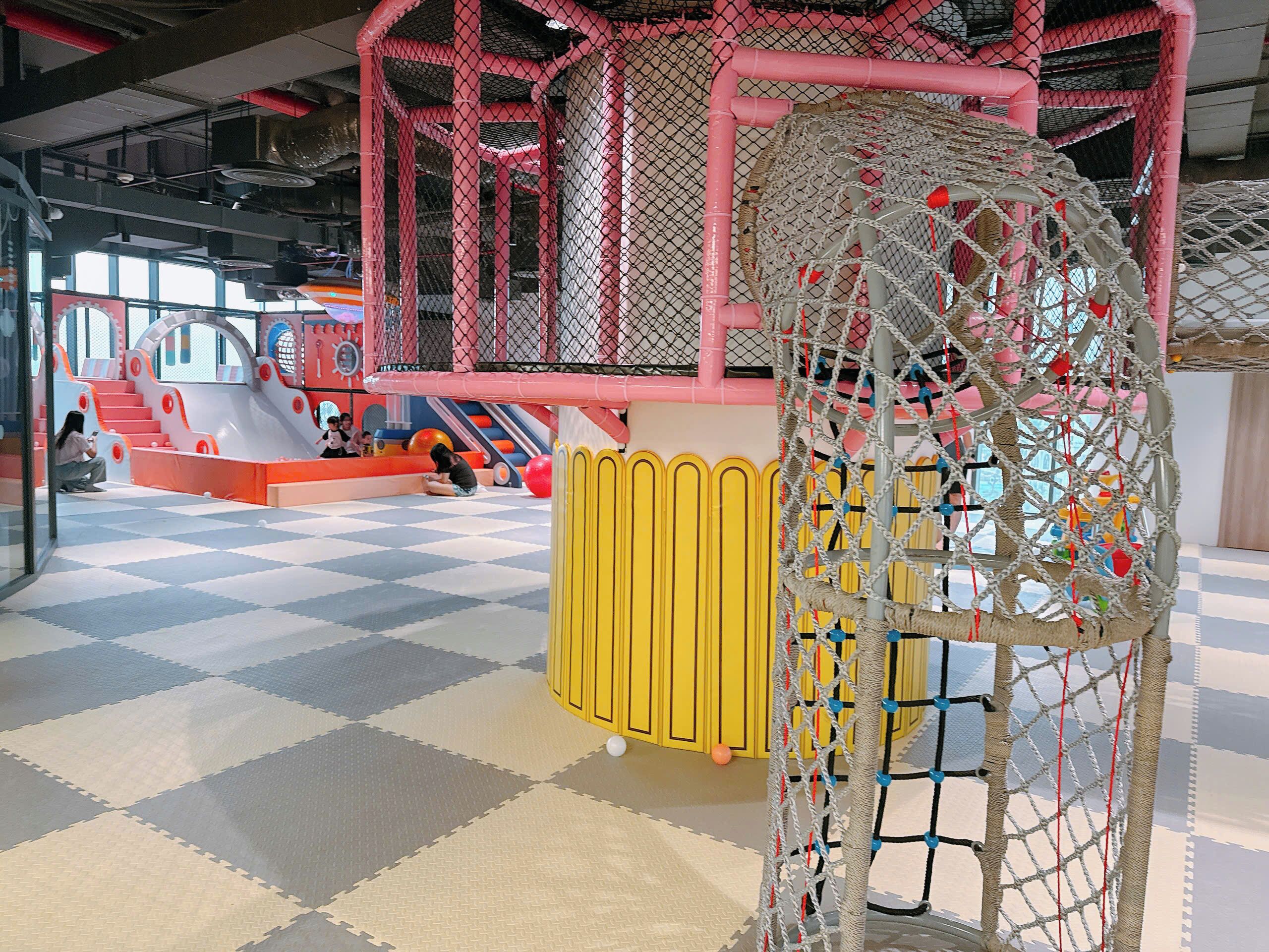 Zona de juegos con estructura de escalada, toboganes y circuito de obstáculos con red.