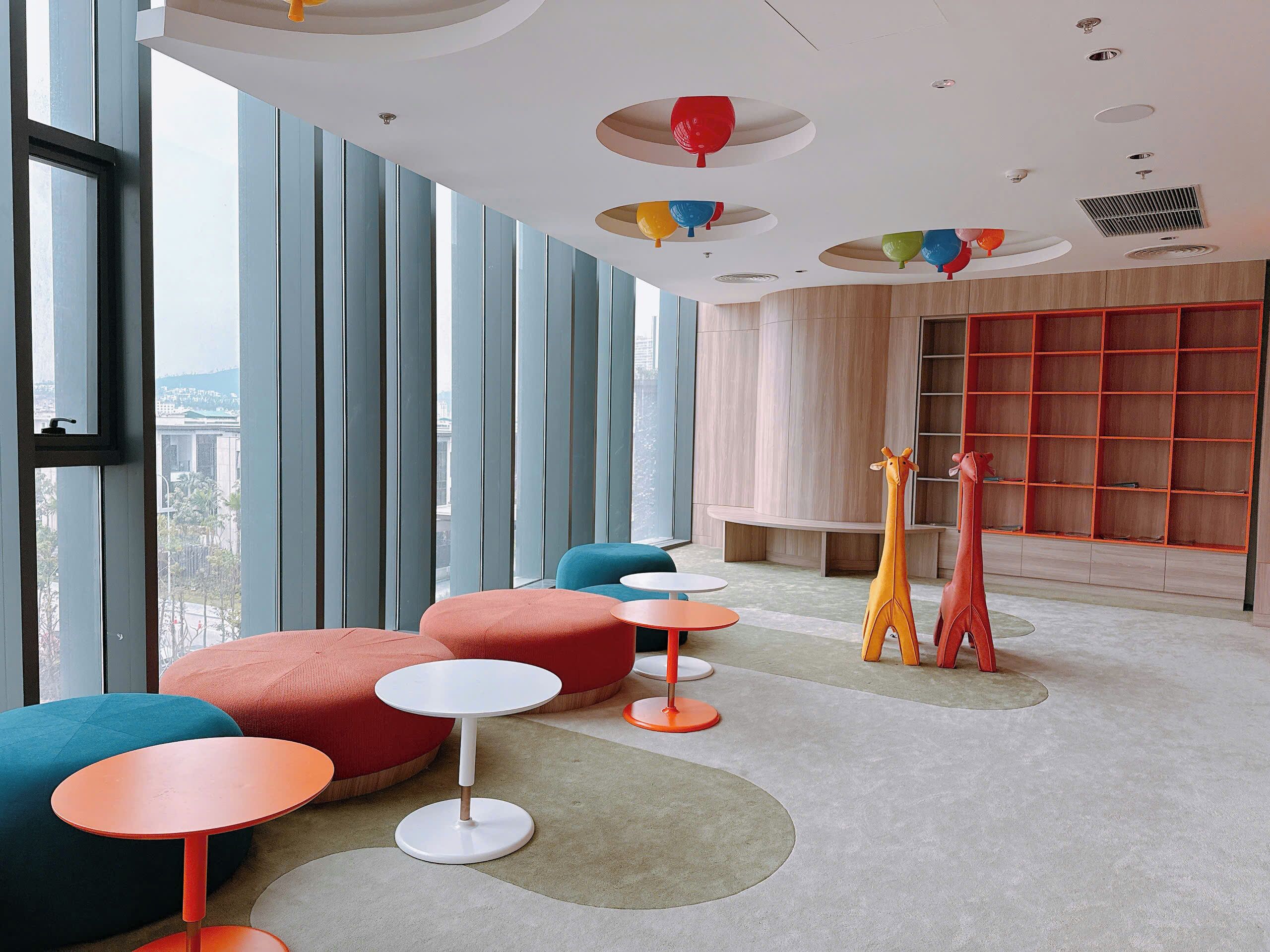 A modern interior with large windows, colorful seating, and a unique ceiling design.