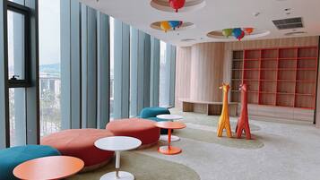 A modern interior with large windows, colorful seating, and a unique ceiling design.