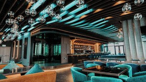 A modern bar area with a curved ceiling, seating with teal cushions, and a visible bar counter. - Alacarte Ha Long Bay Managed by Navis Global (Bai Chay)