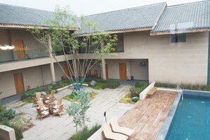 A courtyard with a pool, outdoor seating, and a tree. - Miss or Dismiss (Chongqing)