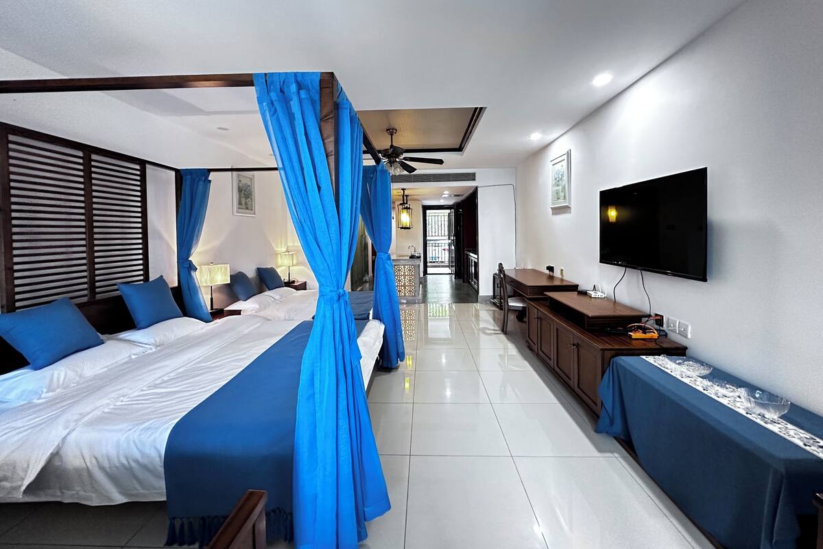 Habitació d'hotel moderna amb un llit gran, televisió, escriptori i bany.