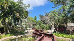 A wooden bridge over a pond with lily pads, surrounded by lush greenery and trees. - GuangPo MeiYa Homestay LingShui (Lingshui)