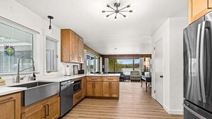 Une cuisine moderne avec des meubles en bois, un réfrigérateur en acier inoxydable et un grand îlot central.