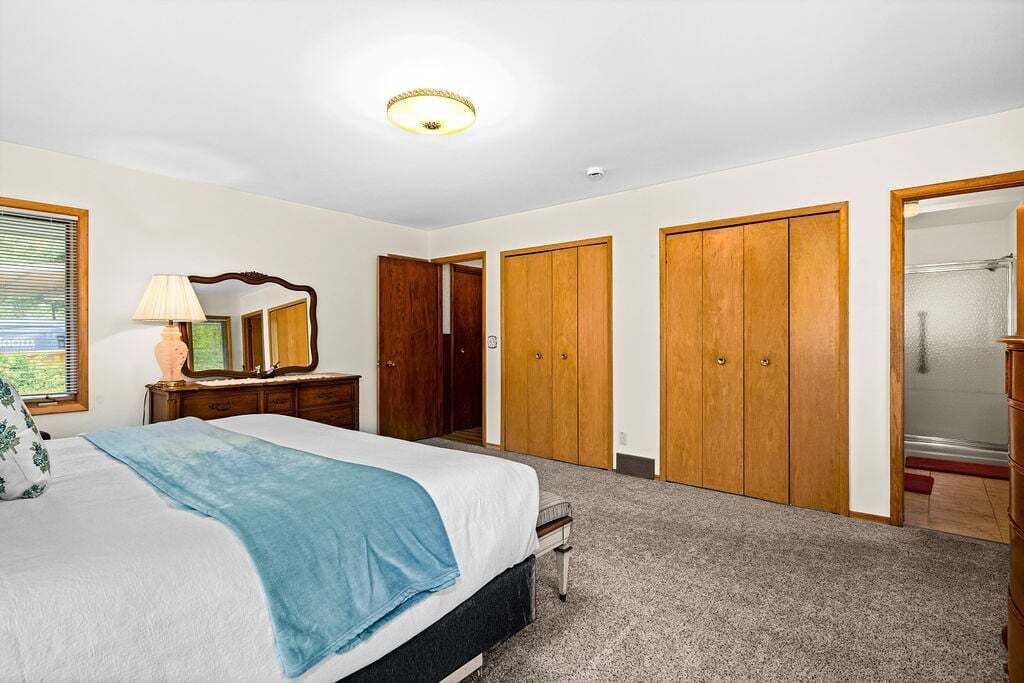 Une chambre à coucher comprenant un lit, une commode, un miroir et un dressing.