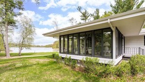 Une maison moderne dotée d’une grande extension vitrée, entourée d’une pelouse bien entretenue et d’arbres.