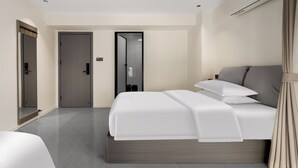 Una camera d'albergo moderna con un letto grande, uno specchio, un armadio e una porta che conduce al bagno.
