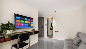 Un soggiorno moderno con una televisione a schermo piatto, un divano, una poltrona e una pianta in vaso.