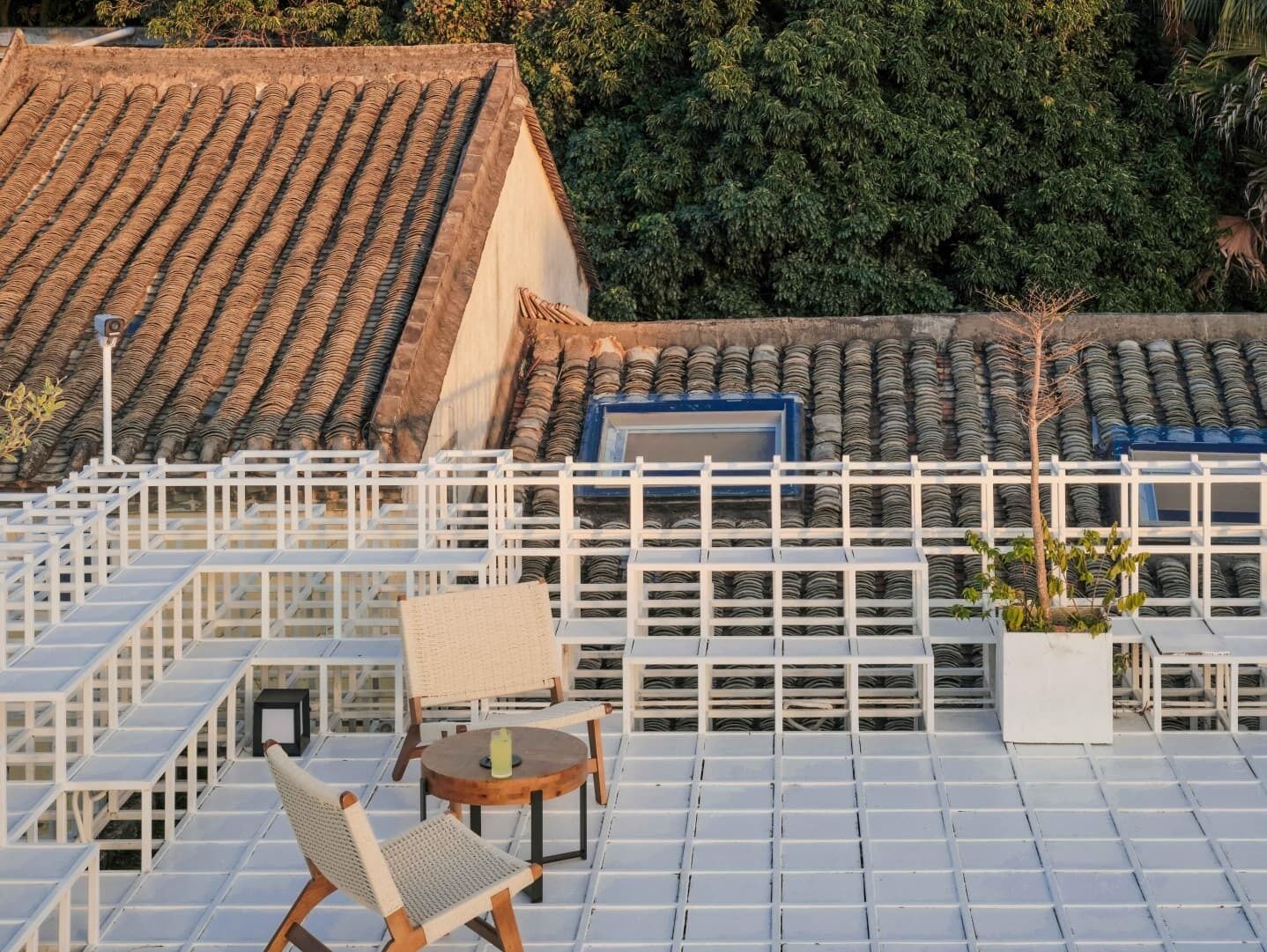 Eine Dachterrasse mit Ziegeldach, weißen Geländern und einer Sitzgelegenheit mit Tisch und Stühlen.