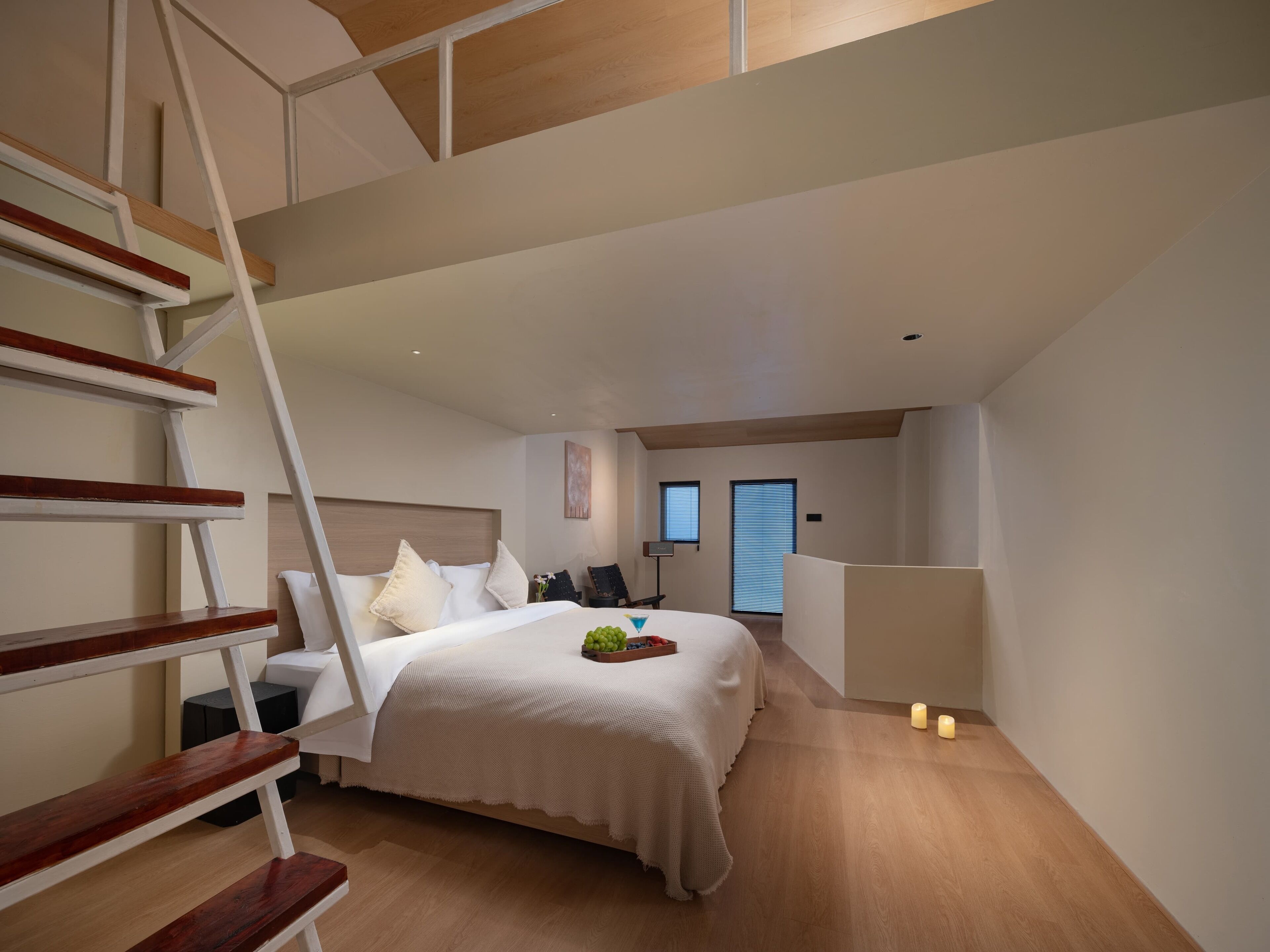 A bedroom with a bed, a wooden staircase, a window, and a door.