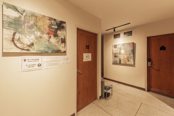 Un pasillo con dos puertas, una con la leyenda 'Solo personal' y otra con un cartel que indica 'Habitaciones de segundo piso A, B, C, D' y 'Subir al tercer piso'.