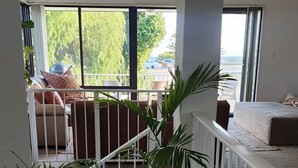 Ein geräumiger Wohnbereich mit Balkon, großen Fenstern und mehreren Blumentöpfen.