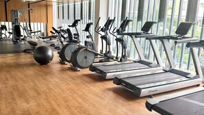 Ein Fitnessstudio mit Laufbändern, Crosstrainern und einem Ergometer.