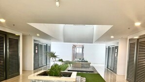 Eine großzügige Lobby mit einer zentralen Wasserspüle, grünem Kunstrasen und modernem Design.