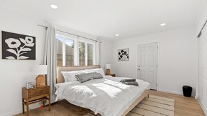 A bedroom with a bed, a nightstand, a lamp, a door, and a window. - 222 - New, Stylish Quiet 2B1B w/ Yard near Stanford (Redwood City)
