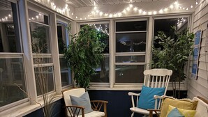A cozy seating area with wooden furniture, a woven pouf, and string lights. - Charming Wisconsin Dells, Devil’s Lake, & Circus World Retreat! (Baraboo)