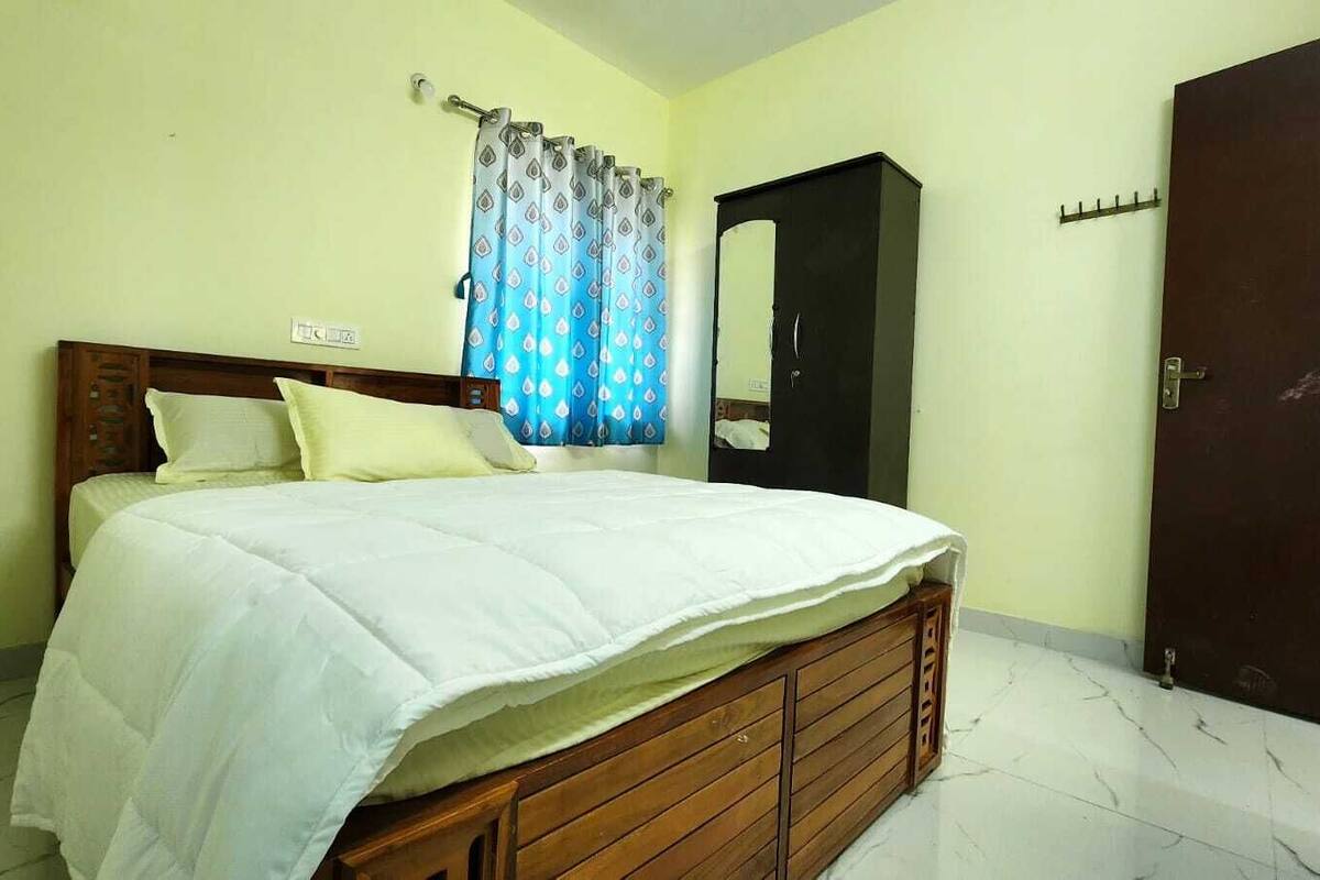 A bedroom with a bed, a wardrobe, a door, and a curtain.