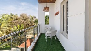 A balcony with artificial grass, white wicker chairs, and a small table. - Golden Ivory by Red Olive (Bengaluru)