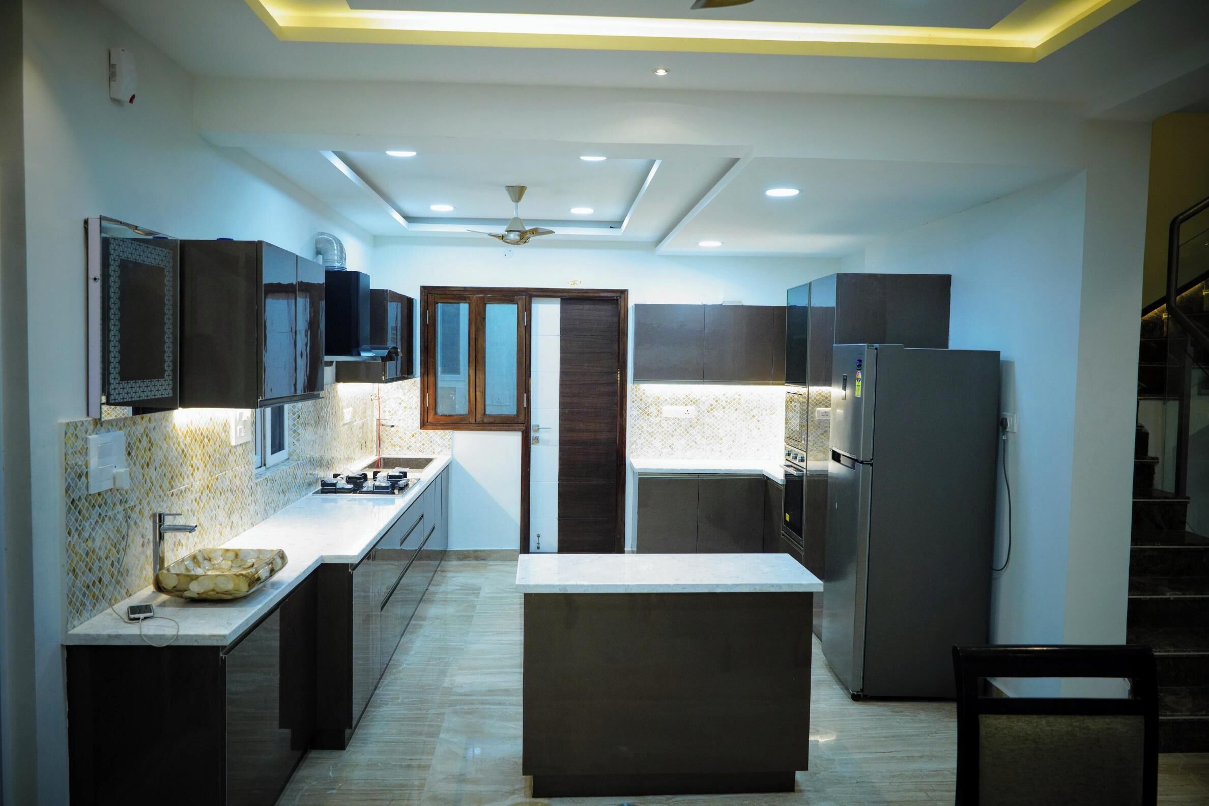 A modern kitchen with a central island, built-in appliances, and a ceiling fan.