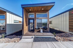 A modern building with a wooden facade, large windows, and a small outdoor seating area with two chairs and a table.