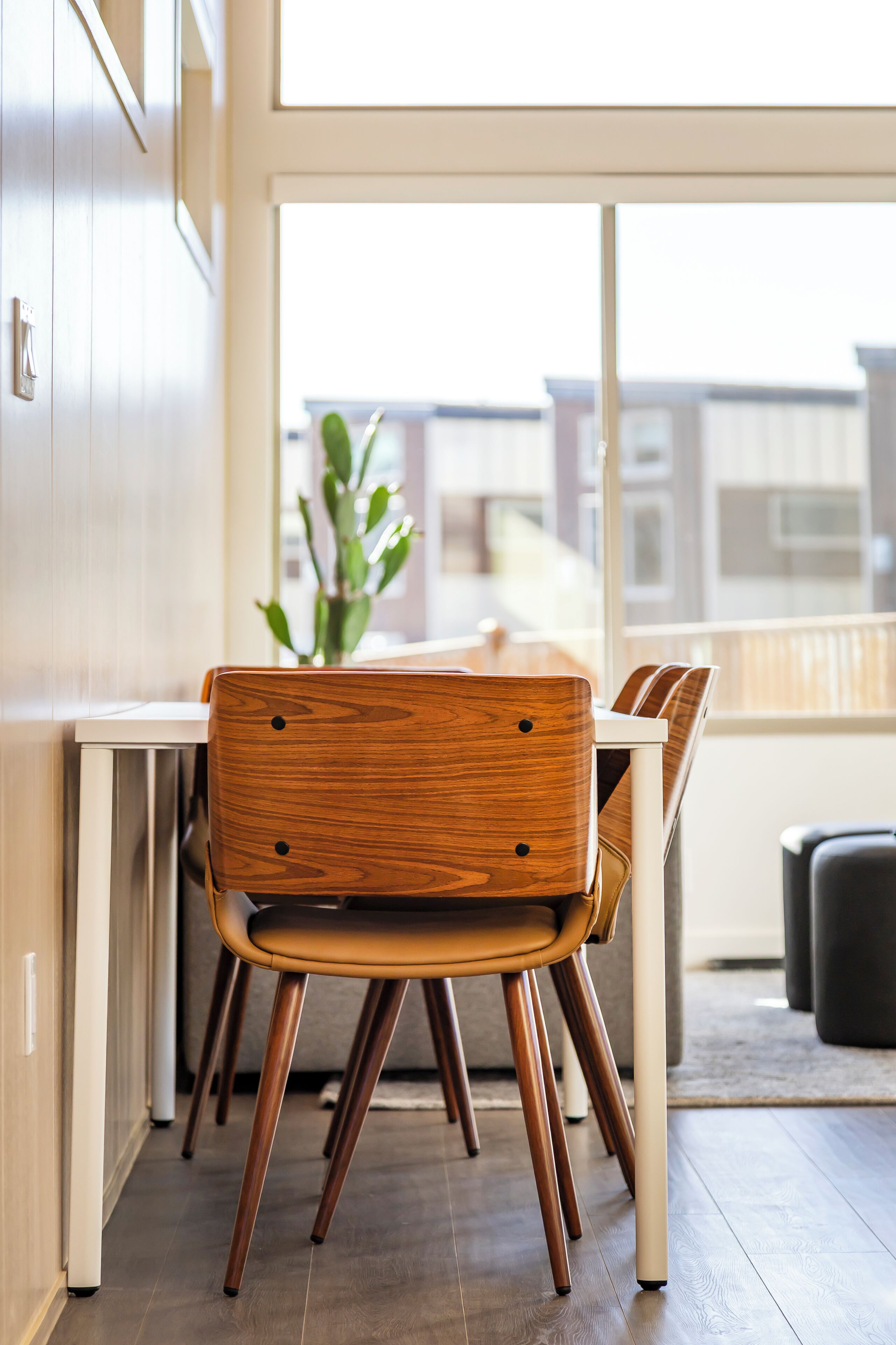 A dining area with a wooden chair, a white table, and a view through a large window.