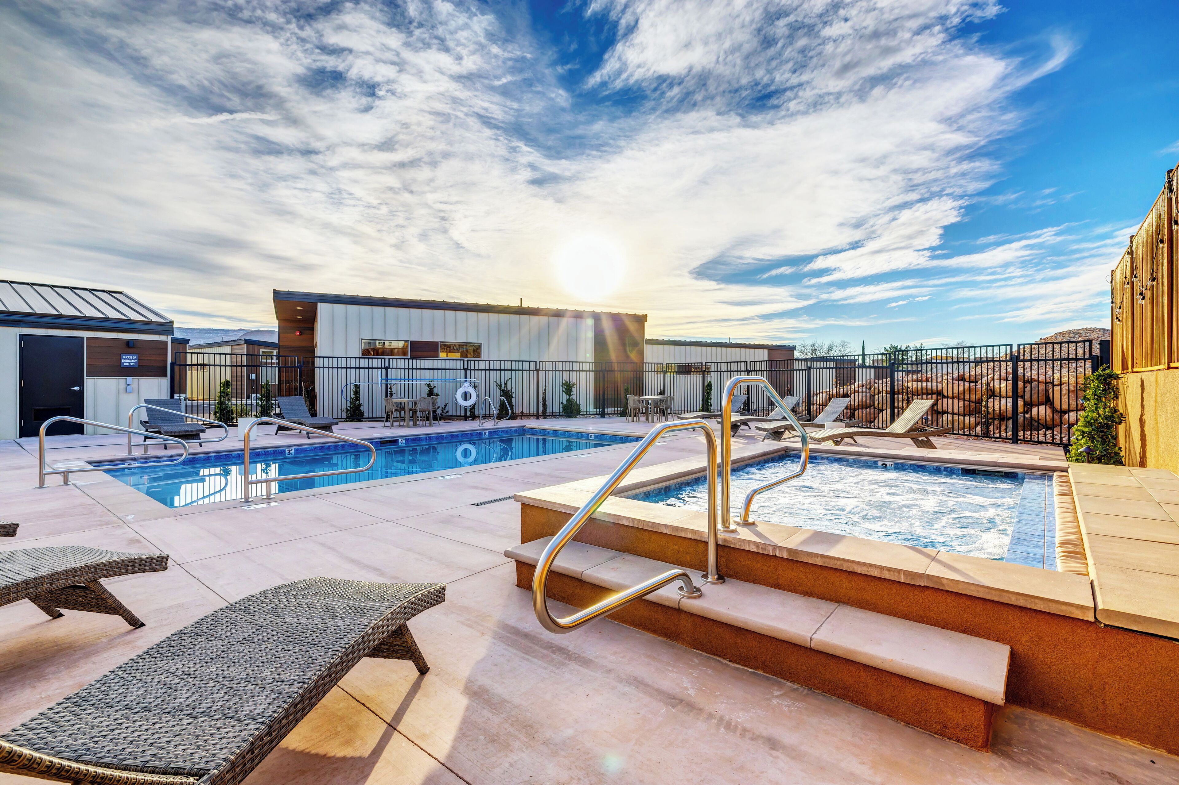 Un espace piscine aménagé sur le toit, avec des chaises longues, un jacuzzi et un bâtiment portant une enseigne.