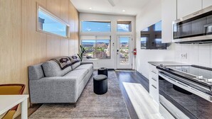 Eine moderne Küche mit Backofen, ein Essbereich mit Sofa und Blick ins Freie.