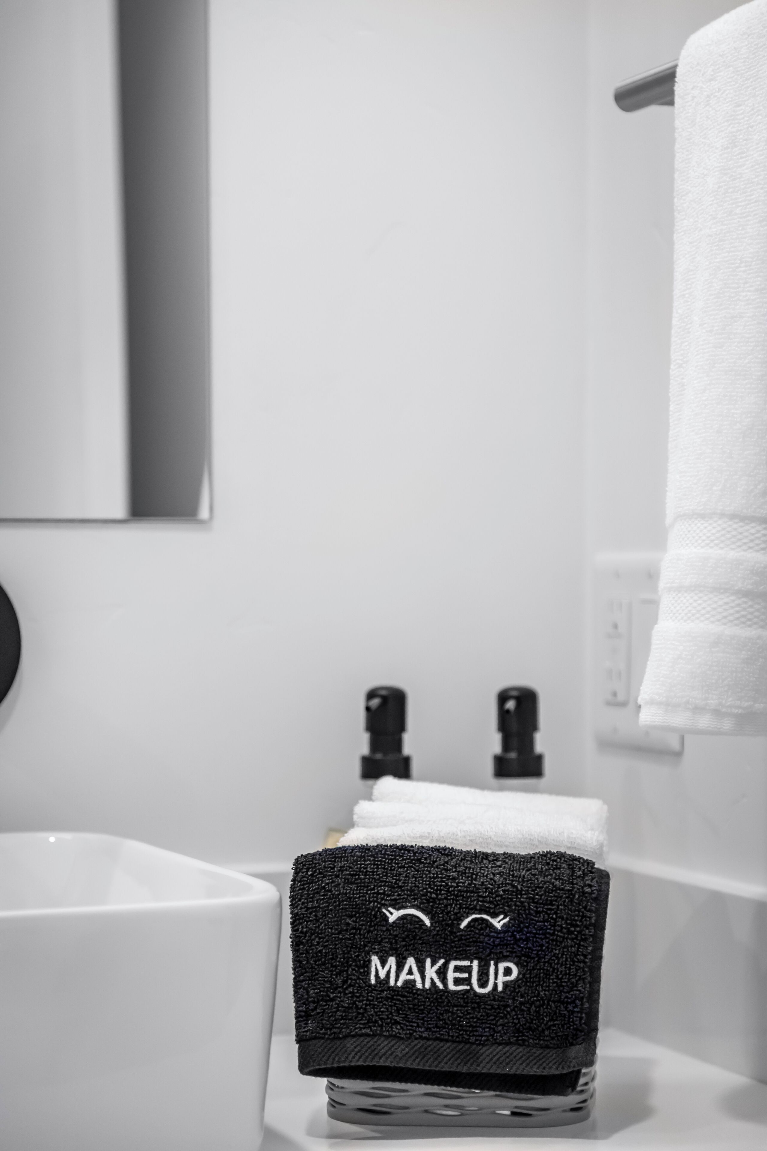 A bathroom with a white sink, a mirror, and a towel rack.