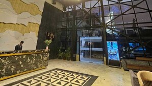 Un hall d’hôtel doté d’un sol à motifs géométriques, d’un comptoir d’accueil et d’un grand lustre.