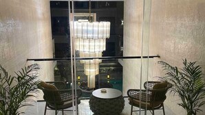 Un intérieur moderne avec une cloison en verre, deux fauteuils en osier, une table ronde et un lustre.