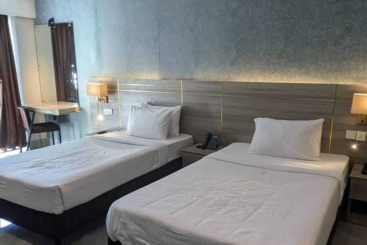 Une chambre d’hôtel avec deux lits, un bureau et une chaise.