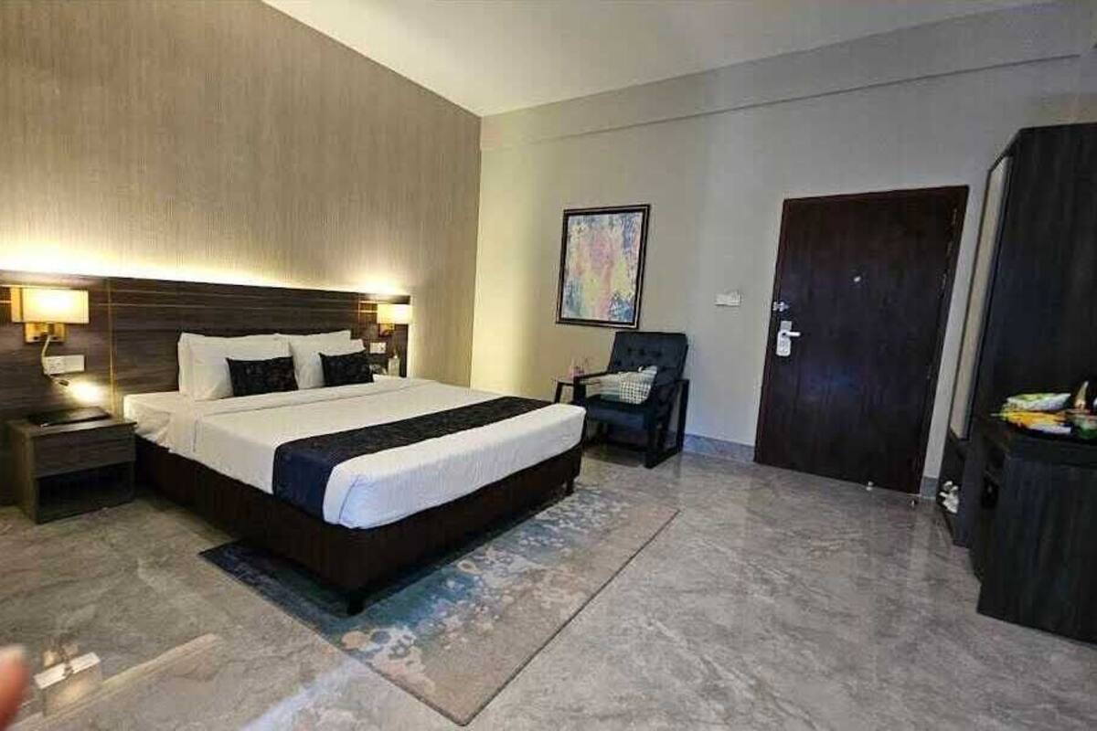 Une chambre d’hôtel moderne avec un grand lit, des tables de chevet, une chaise et une armoire.
