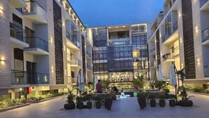 Un atrium d’hôtel moderne doté d’un espace central ouvert, de plantes en pot et d’une personne qui se promène.