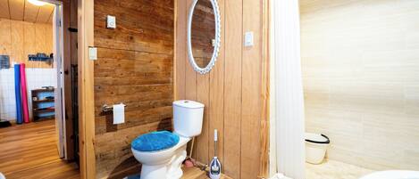 A wooden-paneled bathroom with a toilet, a shower, and a mirror.