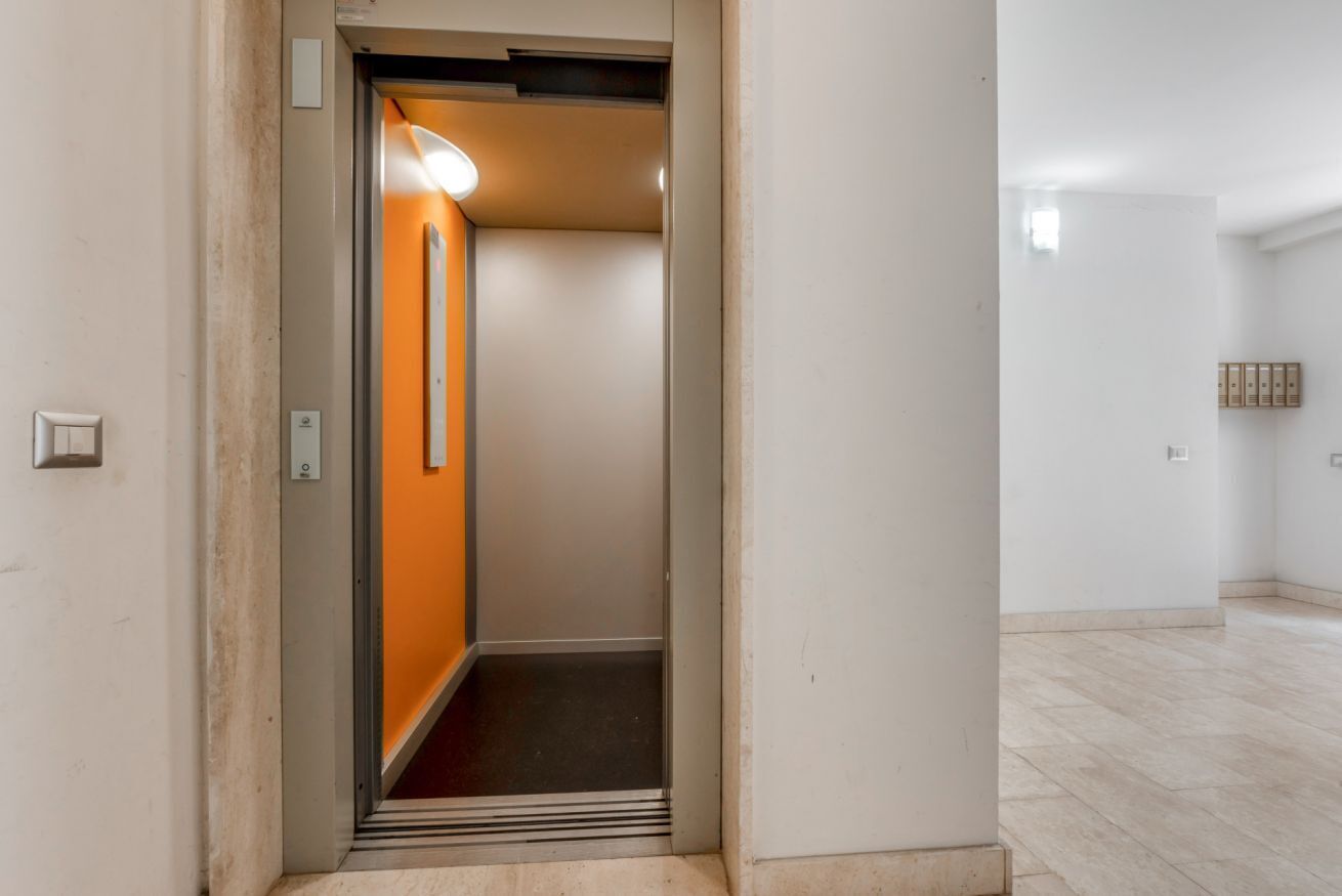 An elevator with a light fixture, a door, and a wall with a switch.
