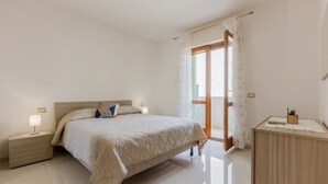 Una camera da letto con un letto, comodini, una cassettiera e una porta scorrevole che dà sull'esterno.