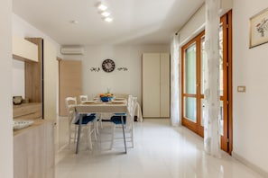 A dining area with a table set for four, a clock on the wall, and a wardrobe in the background. - GuestHost - Located in a quiet area of ​​Cagliari, the apartment offers a welcoming accommodation ideal for those who want comfort and relaxation. With a surface area of ​​60 sqm, it is located on the first floor served by a lift and can accommod (Cagliari)