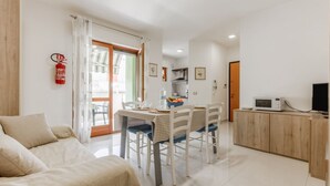 Un ambiente compatto con angolo ristoro, angolo cottura e divano.
