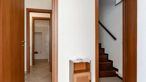 Um corredor com porta de madeira, um pequeno armário de madeira e uma escada.