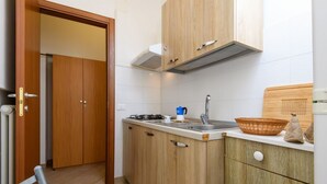 Une cuisine compacte avec des meubles en bois, une cuisinière à gaz, un évier et une planche à découper.